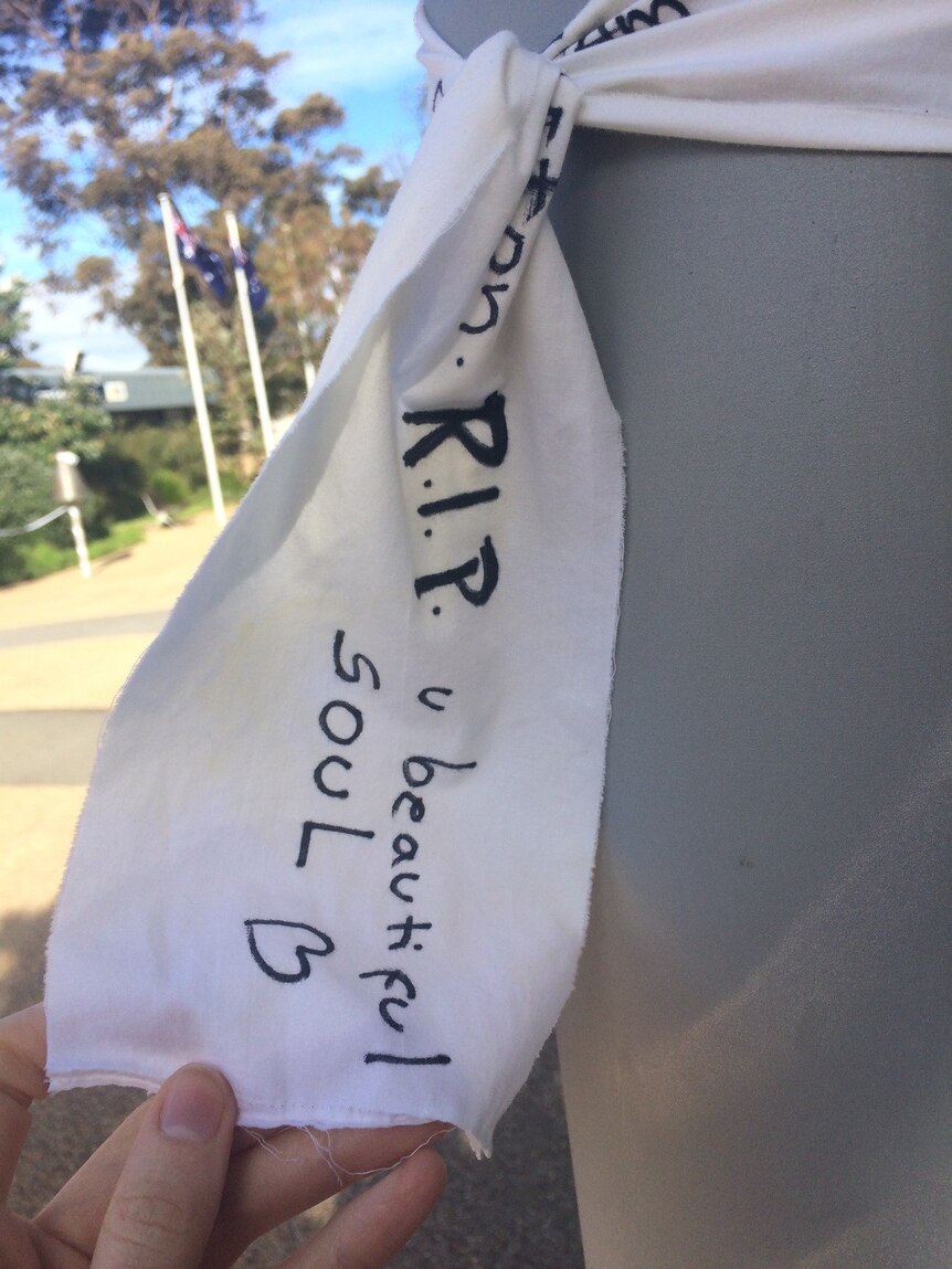 A white cloth cut into a strip with a message tied around a pole.