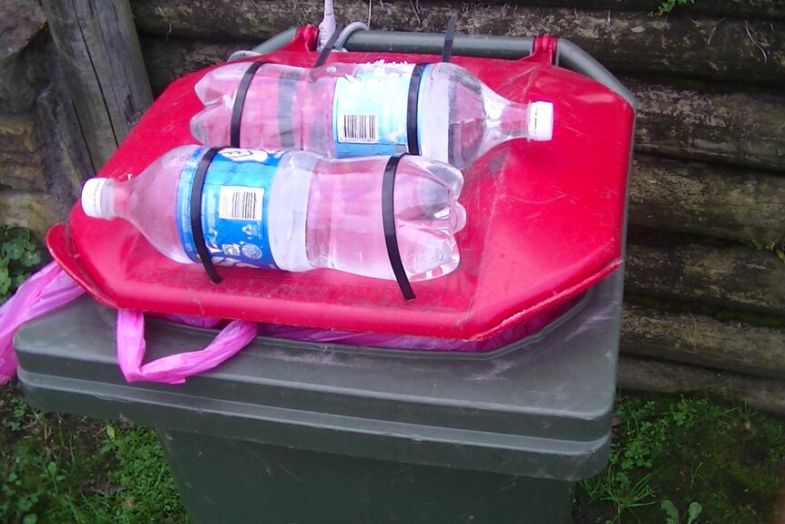 Water bottles strapped to a bin lid 