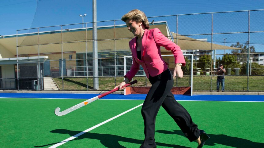 Julie Bishop chases a hockey ball in Brisbane