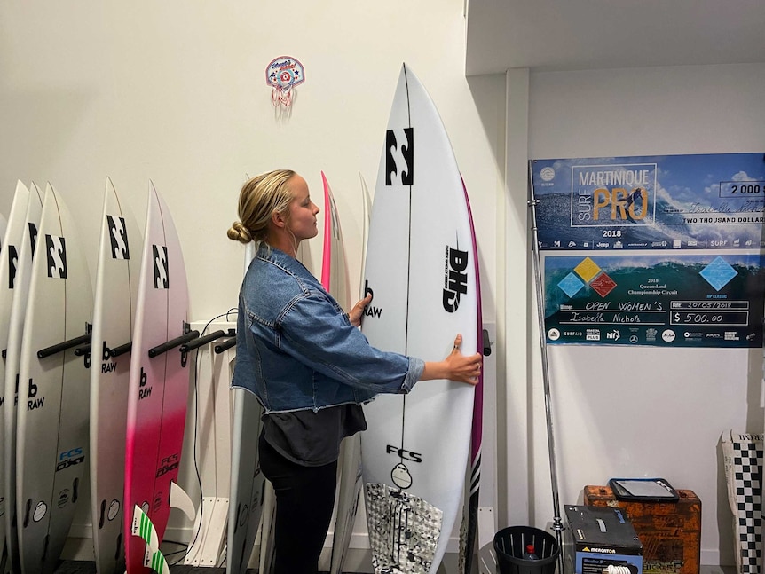 A woman holds a white surfboard