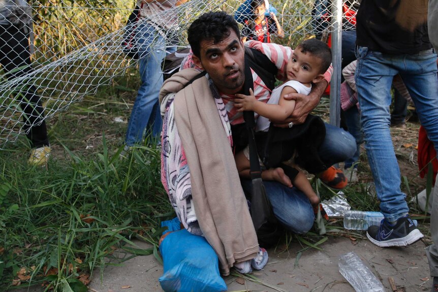 Migrants pass under Hungarian security fence