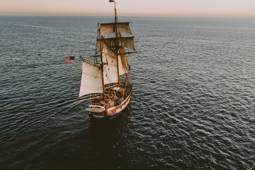 An old ship with sails on the open ocean.
