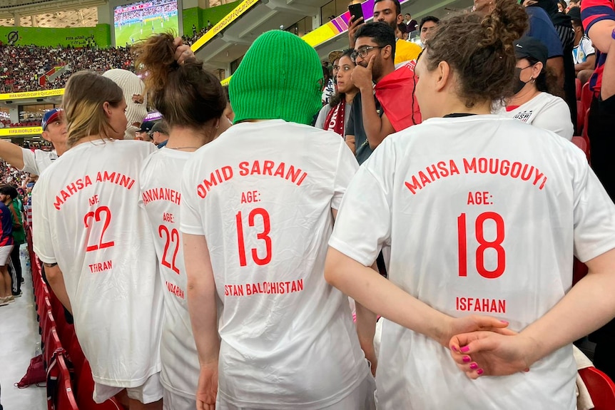 Four young women are dressed in what appear to be satirical football kits bearing names and ages of Iranian women