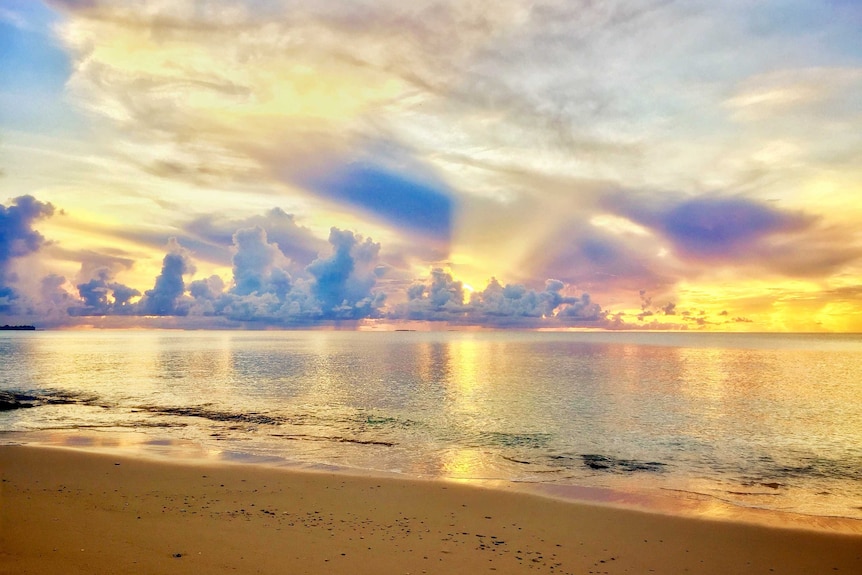 Stunning yellow sunset behind grey clouds over lagoon.