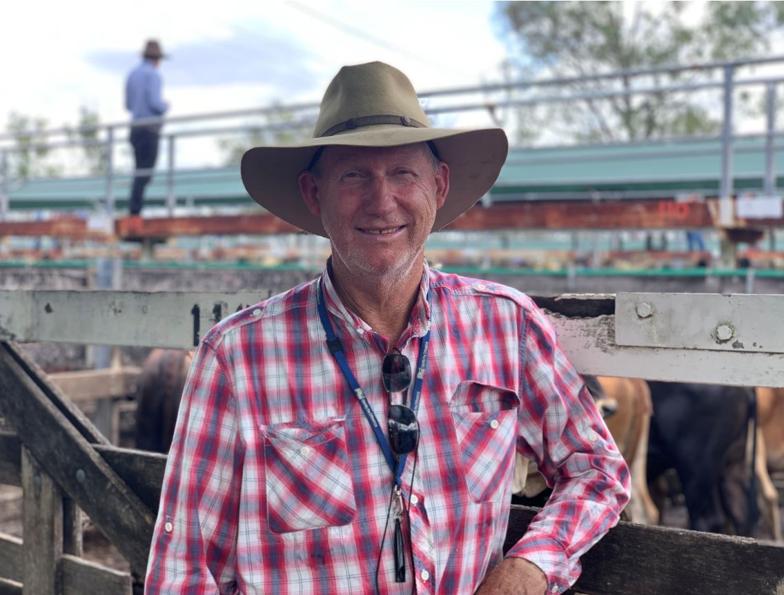 A man in a plaid red, white and blue shirt and an akubra-style hat squinting at the camera
