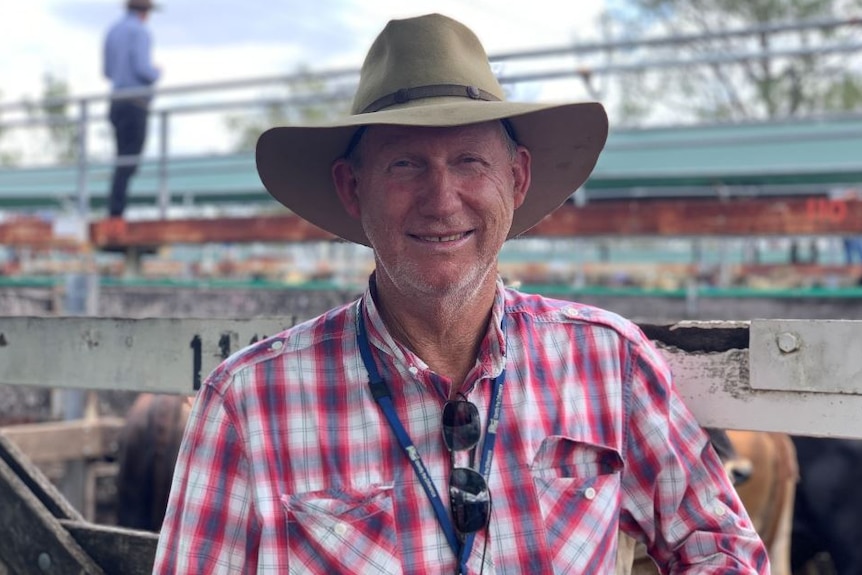 A man in a plaid red, white and blue shirt and an akubra-style hat squinting at the camera