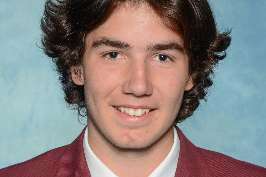 A headshot of a young man in a maroon school uniform