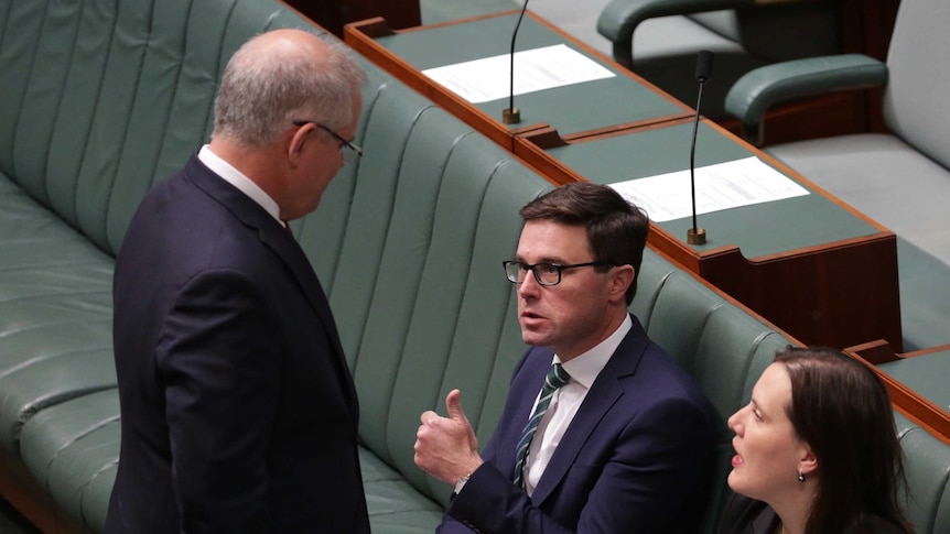 David Littleproud gives a thumbs up while sitting to Kelly O'Dwyer. The Prime Minister stands in front of them talking to them