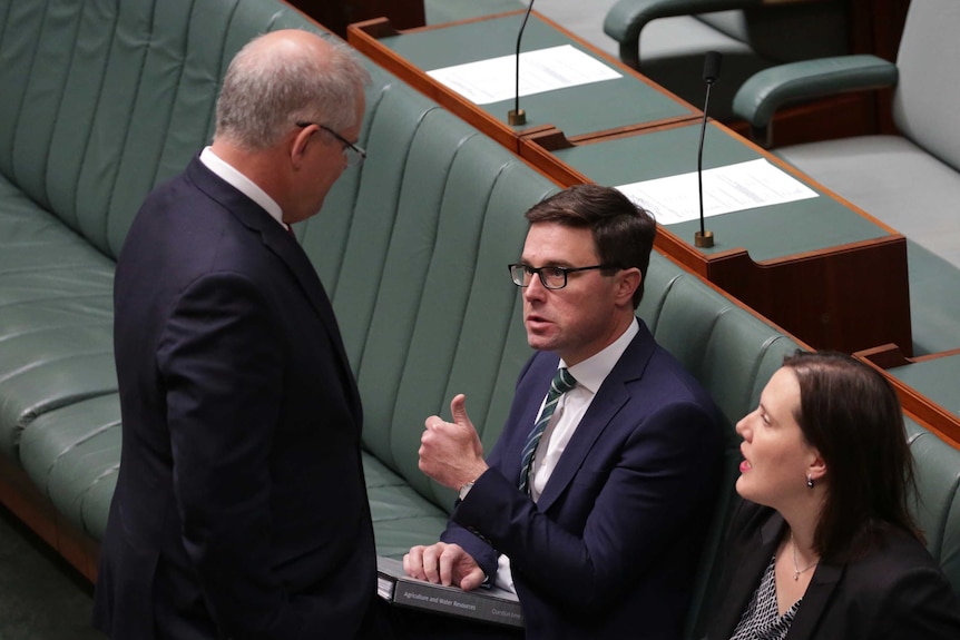 David Littleproud gives a thumbs up while sitting to Kelly O'Dwyer. The Prime Minister stands in front of them talking to them