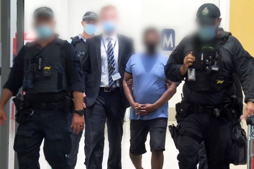 Police and a man in a blue shirt with blurred faces