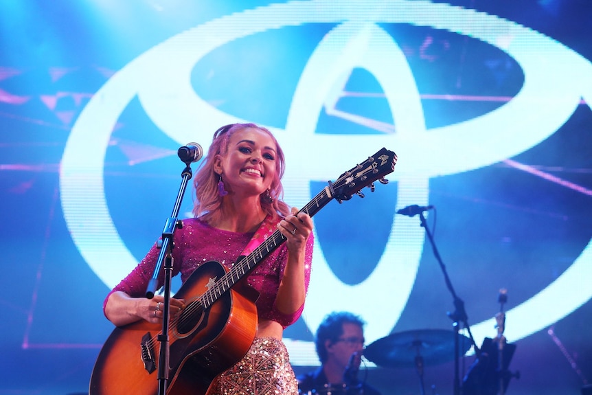 A young, smiling country singer performing.