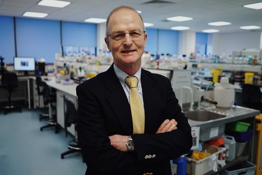 Prof Sir Douglass Turnbull stands, with arms folded, in front of a the mitochondrial research lab at Newcastle University, UK