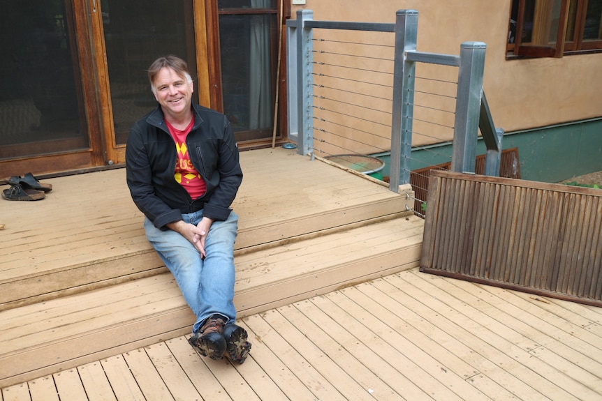 A smiling man sitting on wooden decking
