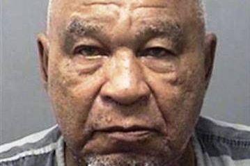 The mugshot of an older man wearing a grey shirt, which appears to be a prison uniform.