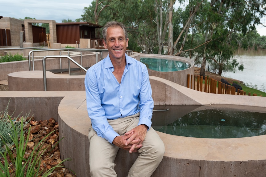 A man sitting on the edge of concrete pools.