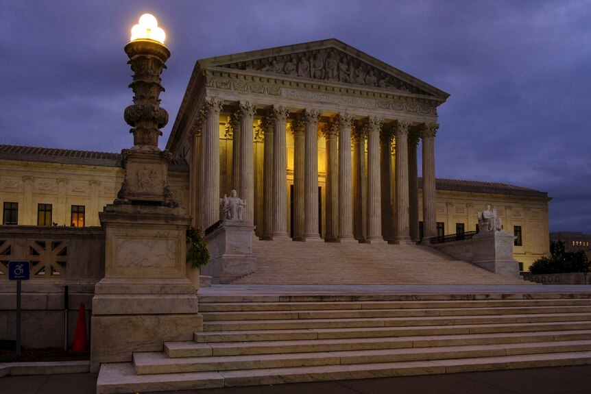 A landscape photograph shows the US Supreme Court shot before sunrise with a moody, overcast purple sky.