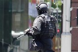 A heavily armed police officer runs across Martin Place.