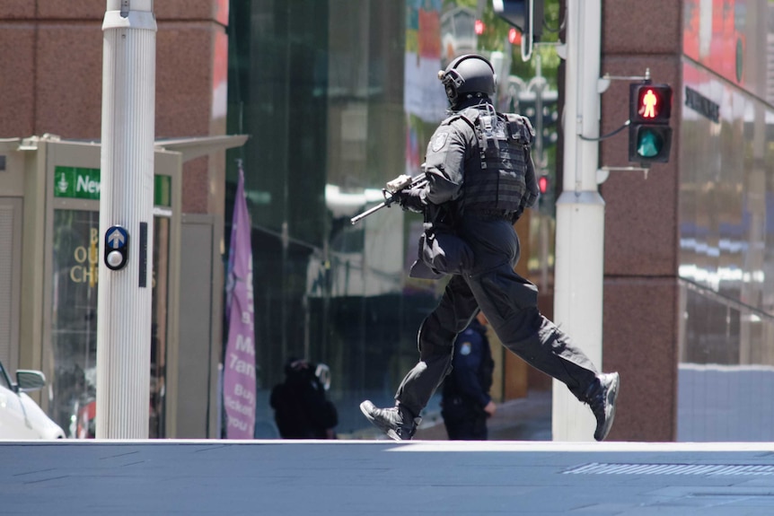 A heavily armed police officer runs across Martin Place.