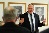 A crowd of heads is visible in front of a gesturing Barnaby Joyce, with a wall of Nationals leaders photos behind him