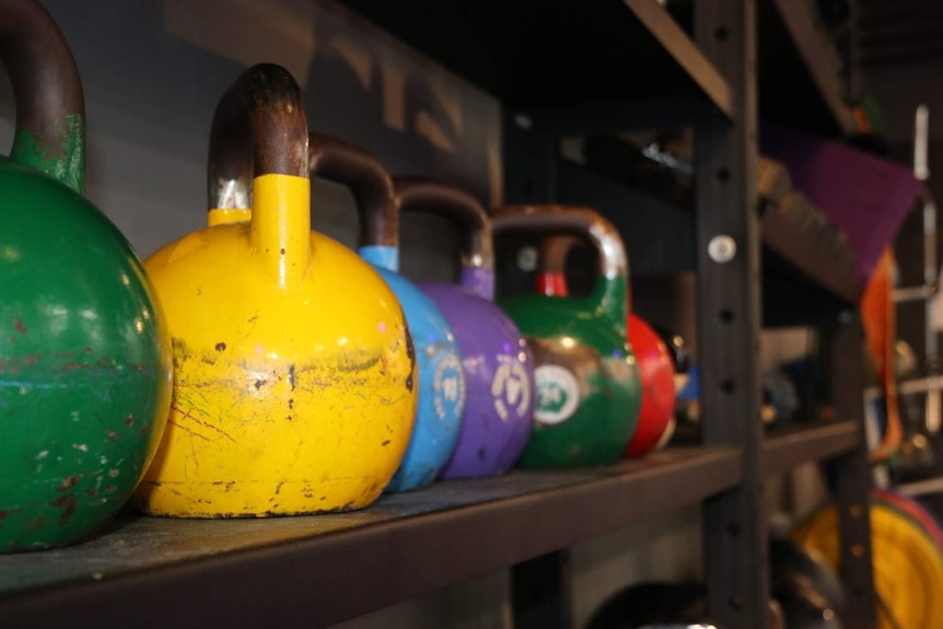 Photo of different coloured kettle bell weights from the side of the storage rack