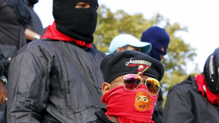 Members of a militant grassroots groups called 'colectivos' stand in a crowd with berets and covered faces