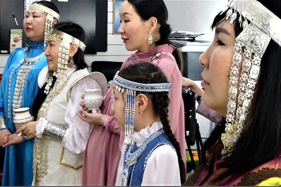 Yakut women wearing traditional high necked dresses and beaded and ornate headwear