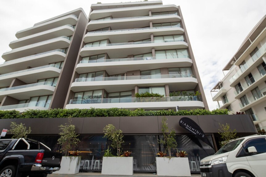 the outside view of a high rise apartment in cronulla with a cafe and restaurant called bianchini on street level