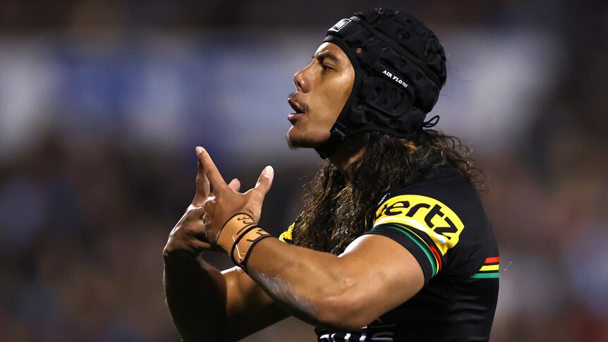 A Penrith Panthers NRL player interlocks his fingers in a gesture of celebration after a try.