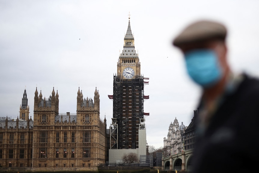 A person wearing a protective face masks walks past Big Ben.