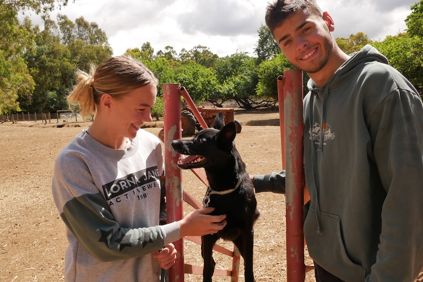 Two people smiling with a happy looking small black dog.