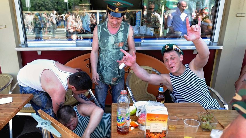 Russian border guard veterans cheer and drink vodka while celebrating Border Guards' Day.