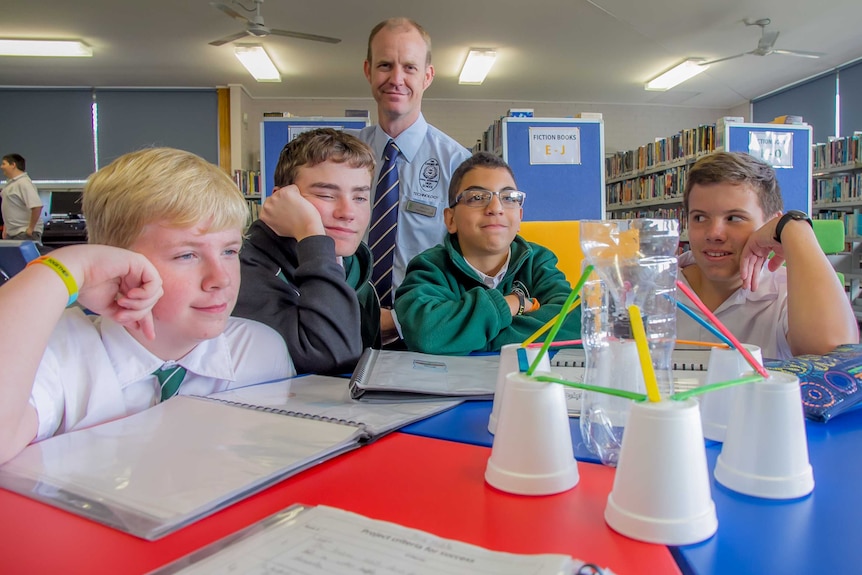 Students looking at a construction made of styrofoam cups, paddle pop sticks and a plastic bottle