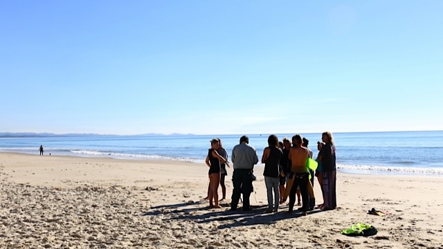 A crowd gathers on the beach at Byron Bay to see a distressed whale rescued.