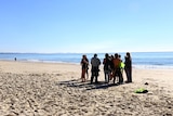 A crowd gathers on the beach at Byron Bay to see a distressed whale rescued.