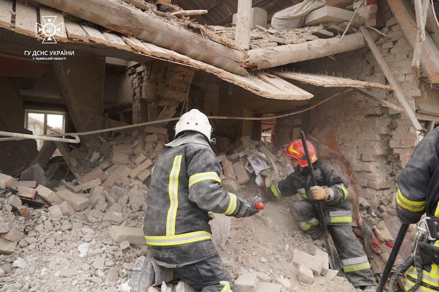 Firefighters dig through rubble of destroyed building.