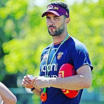 An AFLW coach for the Brisbane Lions watches training. 