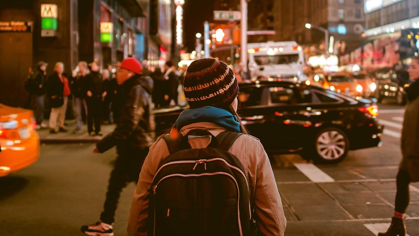 A woman stands at a busy city intersection.