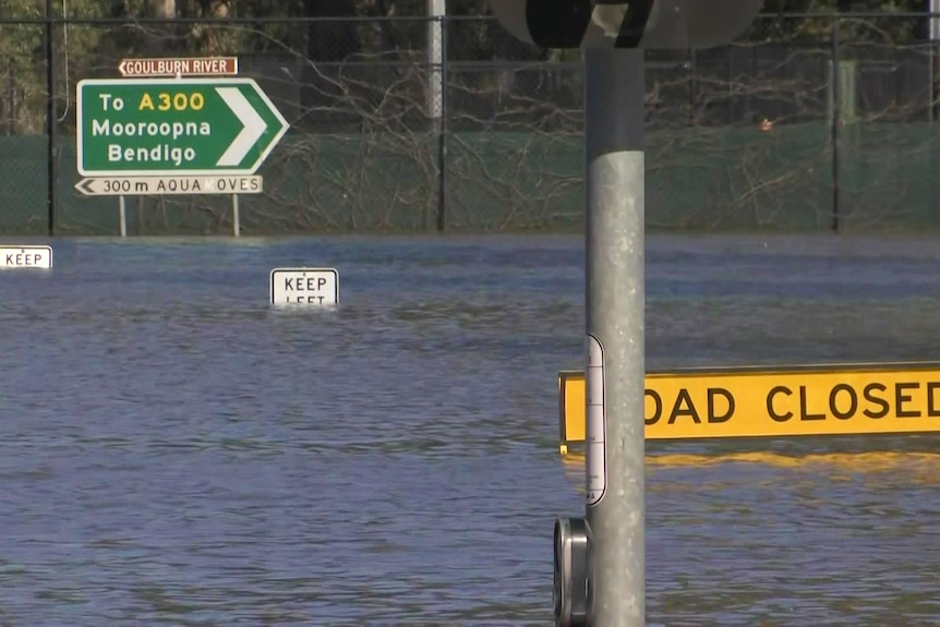 a flooded road with signs that say road closed