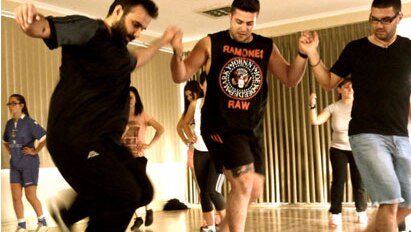 Greek dance teacher Gianni Megalakakis (left) teaches students, including Yianni Rerakis (centre)