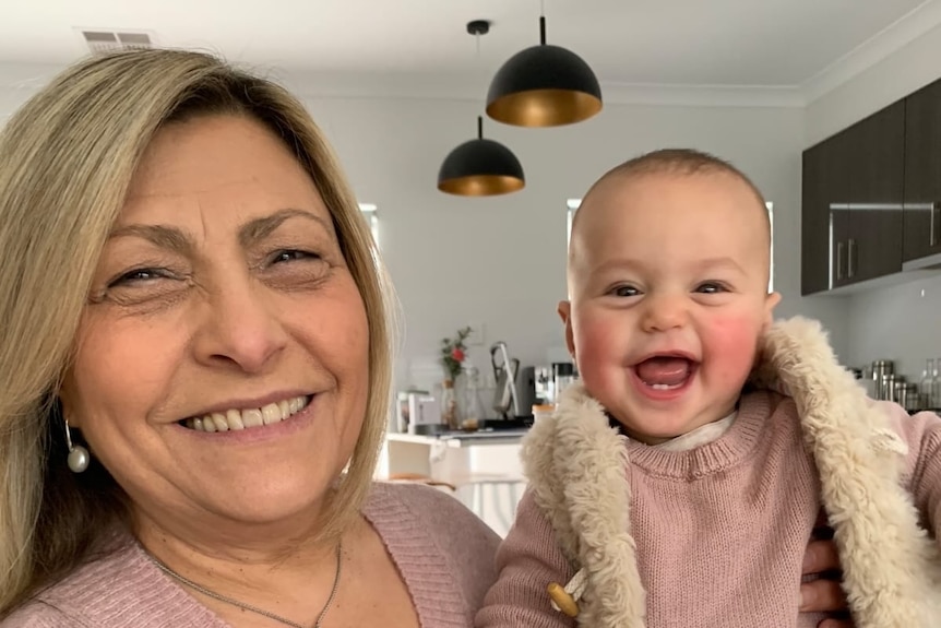 A smiling grandmother holding her baby granddaughter 