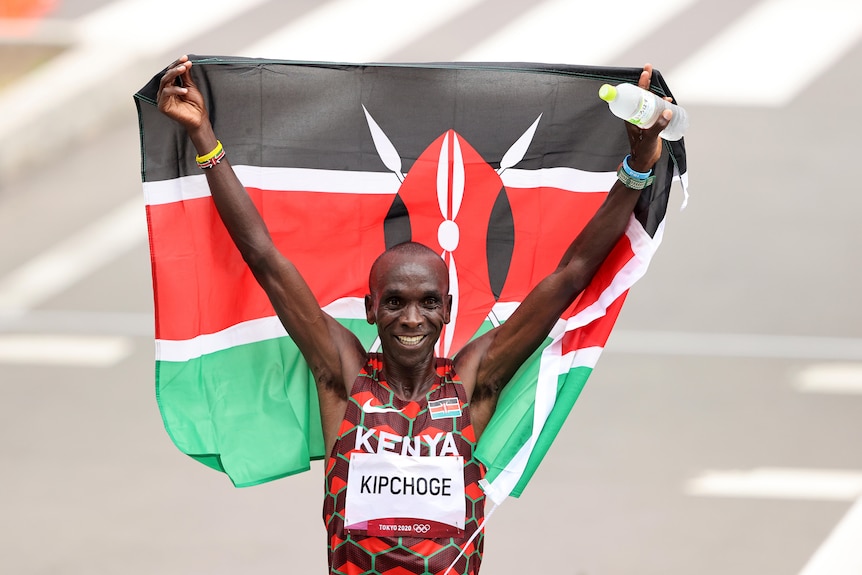 Marathon running holding up Kenyan flag after winning Olympic gold