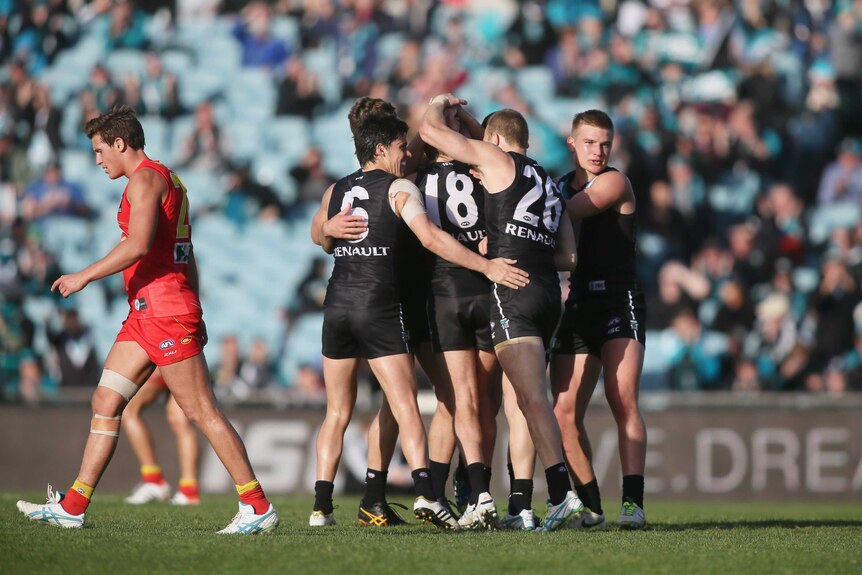 Port Adelaide players celebrate a Kane Cornes goal against Gold Coast.