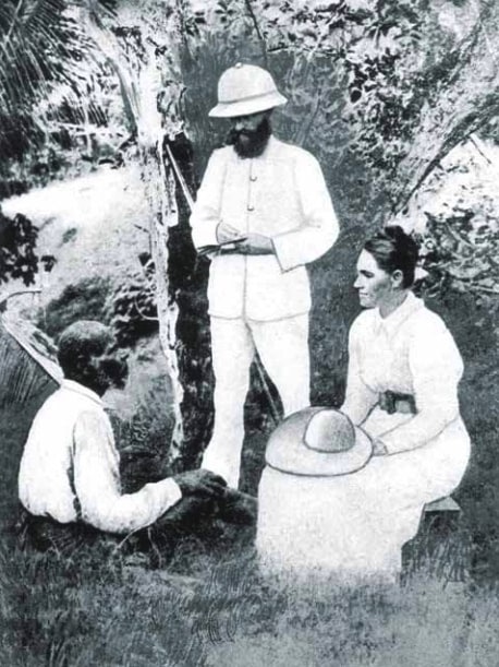 An archival image shows a woman speaking to an Indigenous man, while another man stands nearby, taking notes.