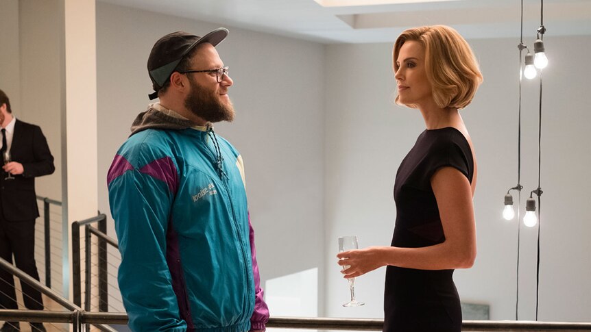 Colour still of Seth Rogen wearing windbreaker and Charlize Theron wearing black dress at black tie event 2019 film Long Shot.