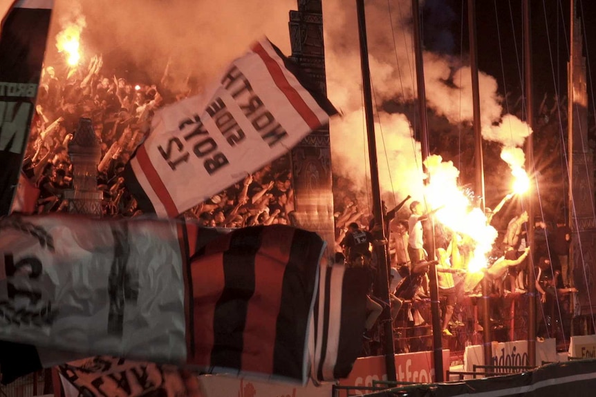 Fans light flares and scream in the stands.