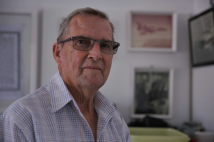 An elderly man with glasses on looking at the camera