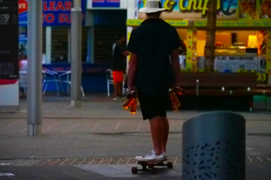 man on skakeboard with beers in hand