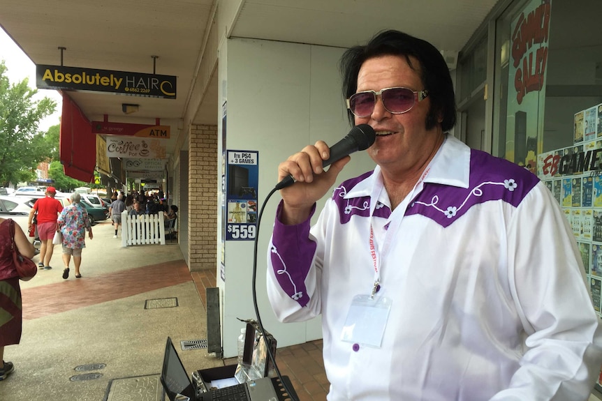 Elvis Presley impersonator buzzing outside of a shop