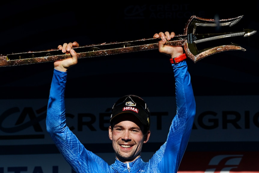 Primoz Roglic holds a trident above his head