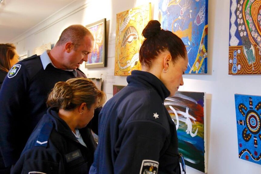Police looking at artworks on display in an exhibition by Indigenous prisoners